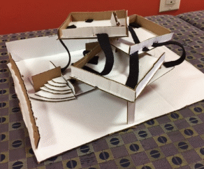 Photo showing Brenda's structure, a three-tiered cardboard object with black felt and graduated platform.