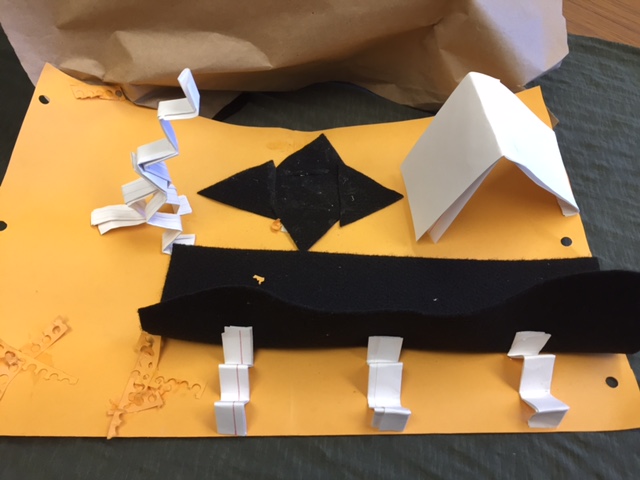 Photo showing all pieces of John's structure, consisting of yellow cardstock onto which black felt and white index card shapes are glued.